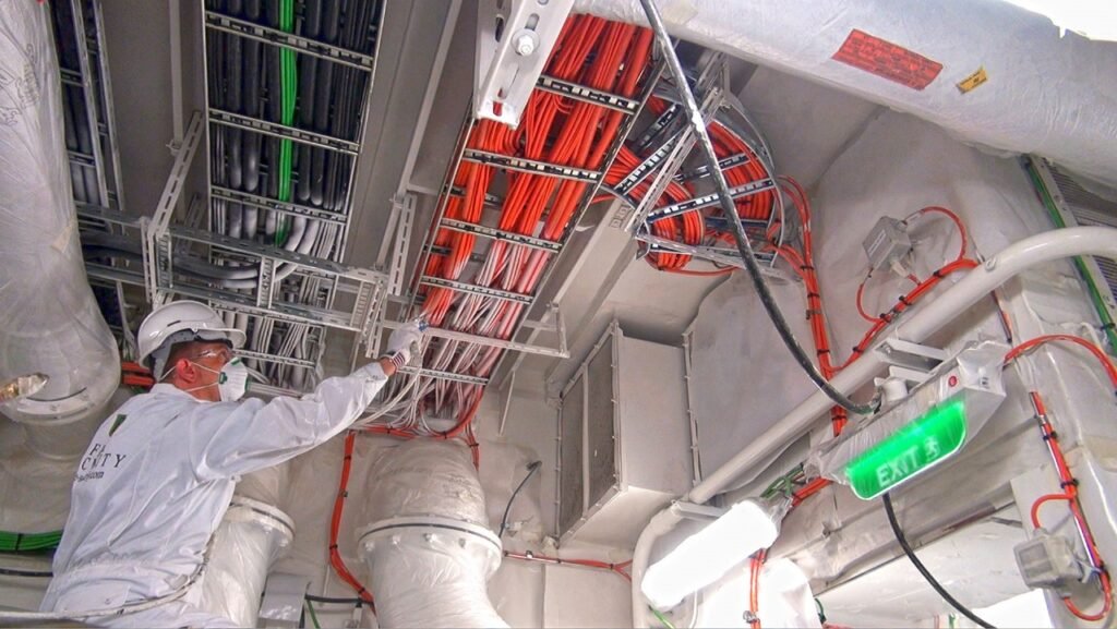 Technician applying intumescent fire-rated cable coating on electrical cables for passive fire protection in Saudi Arabia